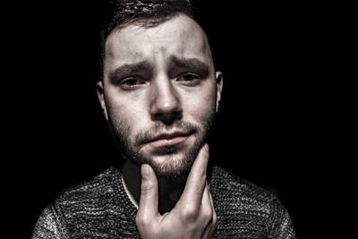 Close-up portrait of young man against black background