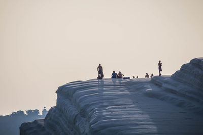 People on mountain against clear sky