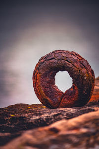 Close-up of rusty metal on rock against sky