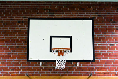 Low angle view of basket hoop mounted on brick wall