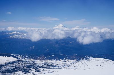 Aerial view of snowcapped mountains against blue sky