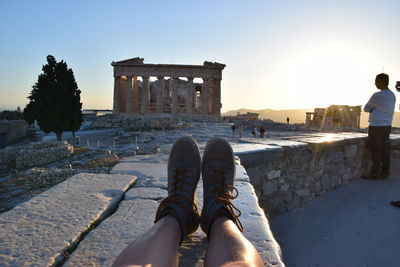 Low section of tourists wearing shoes sitting against architectural columns