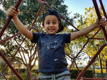 Portrait of smiling boy standing on jungle gym at playground