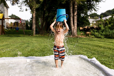 Young boy pouring water bucket over head