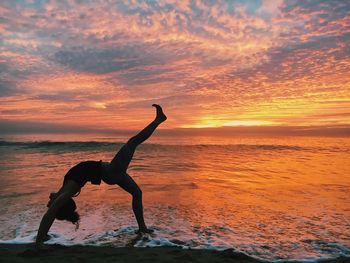 Silhouette person on beach against sky during sunset