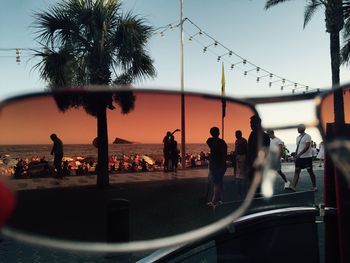 People at observation point seen through sunglasses against sky