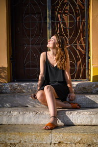 Full length of young woman sitting outdoors