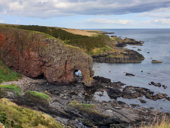 Scenic view of rock formation and sea against sky