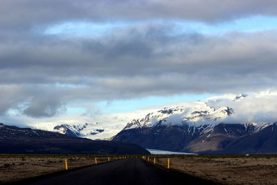 Empty road against snow covered rocks