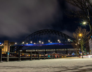 Illuminated bridge over street against sky at night