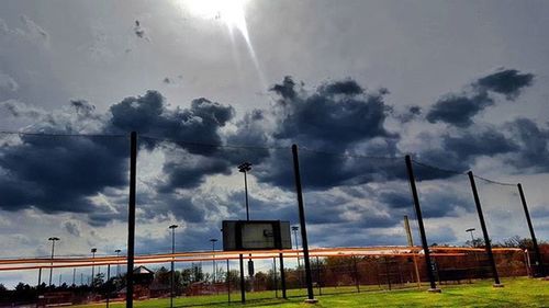 View of field against cloudy sky