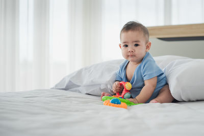 Portrait of cute baby boy lying on bed at home