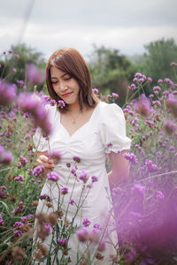 Portrait of young woman standing amidst plants