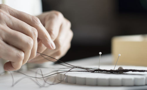 Cropped hands of woman working with thread on table