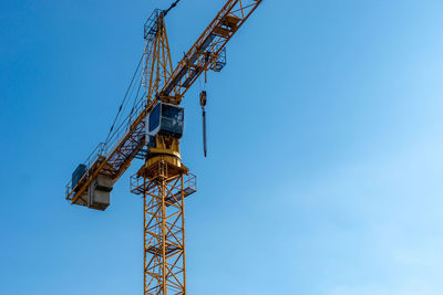 Low angle view of crane against clear blue sky