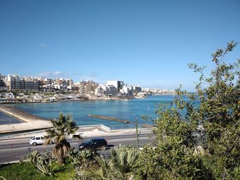 Scenic view of sea and buildings against clear blue sky