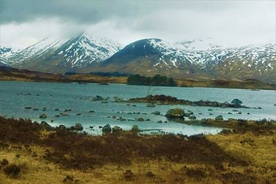 Scenic view of lake by snowcapped mountains against sky