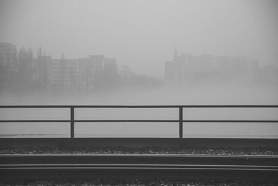 Railroad tracks in foggy weather against sky during winter