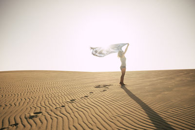 Rear view of man standing on sand at beach