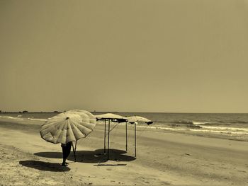 Rear view of people on beach against clear sky