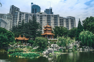 Buildings by lake against sky in city