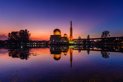 Reflection of mosque in lake against sky during sunset