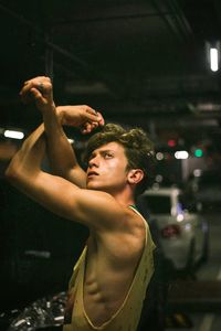 Young man looking away while standing in parking lot