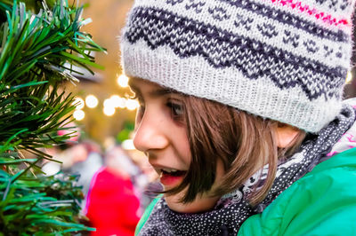 Close-up of smiling girl by christmas tree