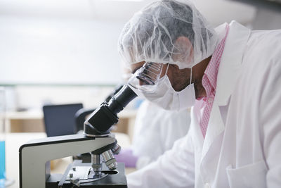 Man scientist looking through microscope at laboratory