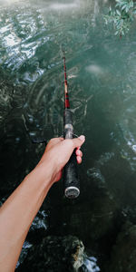 High angle view of person holding rock in lake