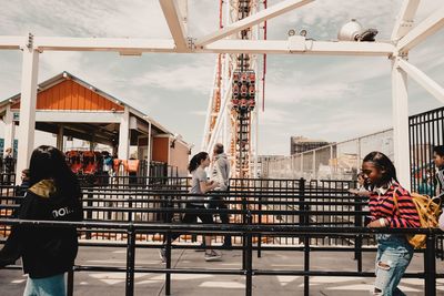 People standing by railing in city against sky