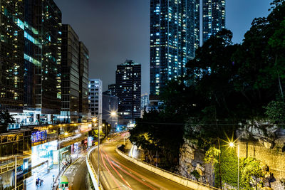 Light trails on city street amidst buildings at night
