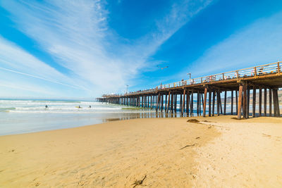 Pier on beach against blue sky