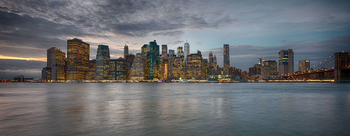 City at waterfront against cloudy sky