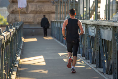 Rear view of man walking on footpath