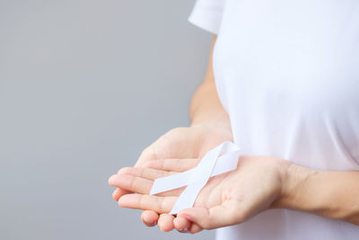 Midsection of woman holding paper against white background