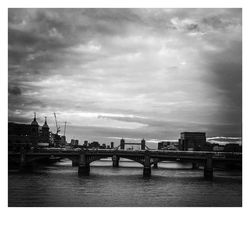 Bridge over river against cloudy sky