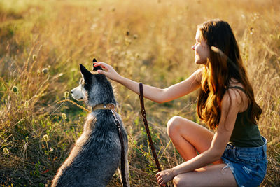 Side view of woman with dog on grassy field