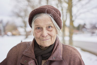 Portrait of senior woman against bare trees during winter