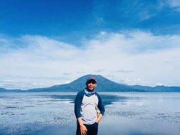 Portrait of young man standing on mountain against sky