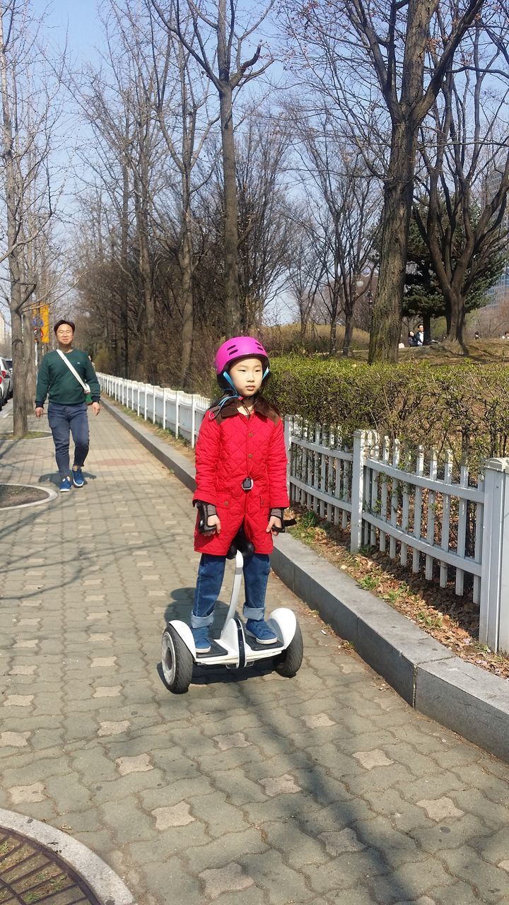 full length, real people, boys, lifestyles, day, childhood, leisure activity, looking at camera, bare tree, outdoors, tree, elementary age, headwear, helmet, happiness, warm clothing, portrait, smiling, sports helmet, cycling helmet, people