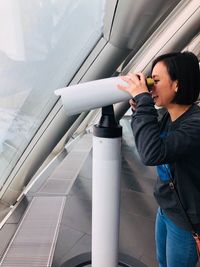 Young woman looking through coin coin-operated binoculars