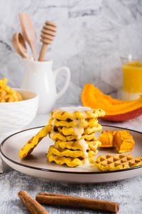 A stack of belgian homemade pumpkin waffles topped with sweet sauce on a plate on the table