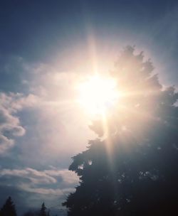 Low angle view of sun shining through clouds