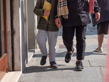 Detail of a parent holding hands with his son walking down a city street.