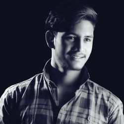 Portrait of young man against black background