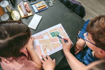 Cropped hand of mother showing map to kids