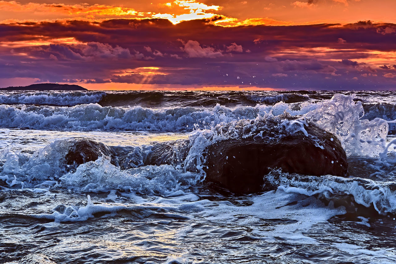 WATER SPLASHING IN SEA AGAINST SKY