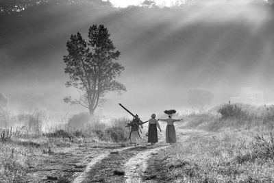 Women walking on field against sky