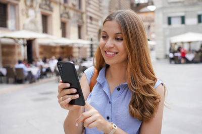 Young woman using mobile phone on street